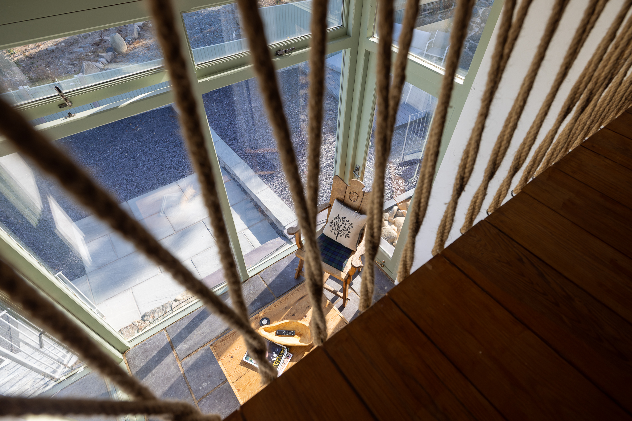 A view through the rope balustrade into the light-filled cottage below